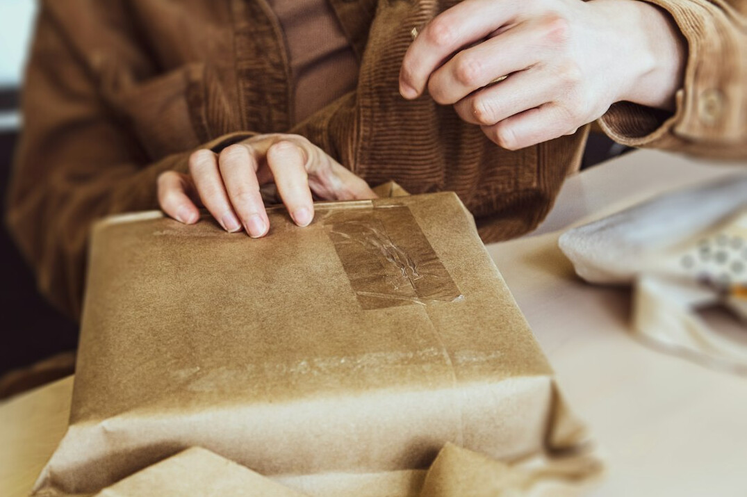 Retail employee packing an online order in a bright fulfilment room