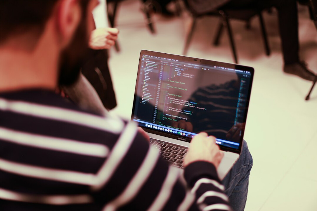 programmer writing code on laptop