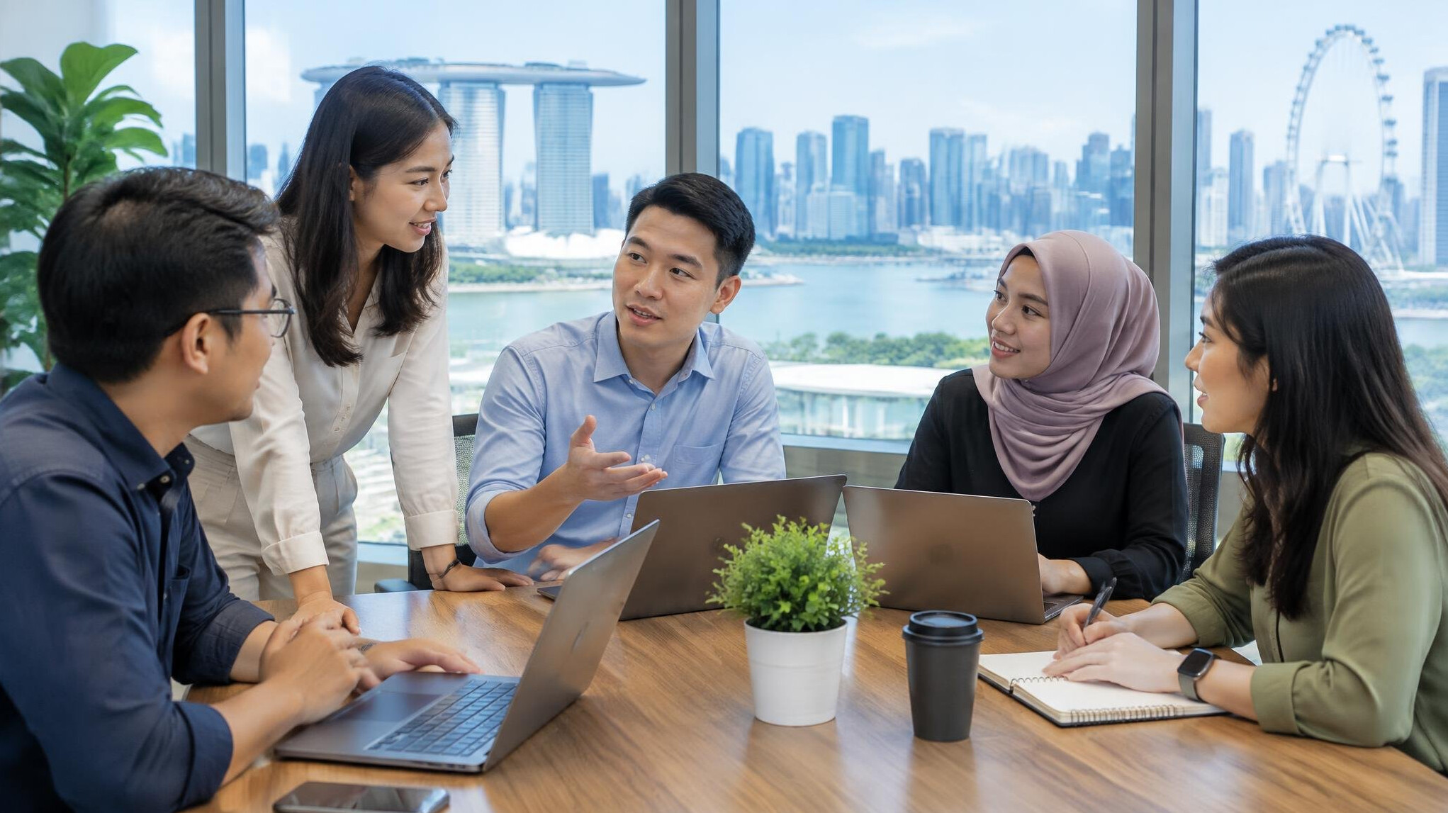 Diverse engineering team collaborating around a table with laptops in a bright office